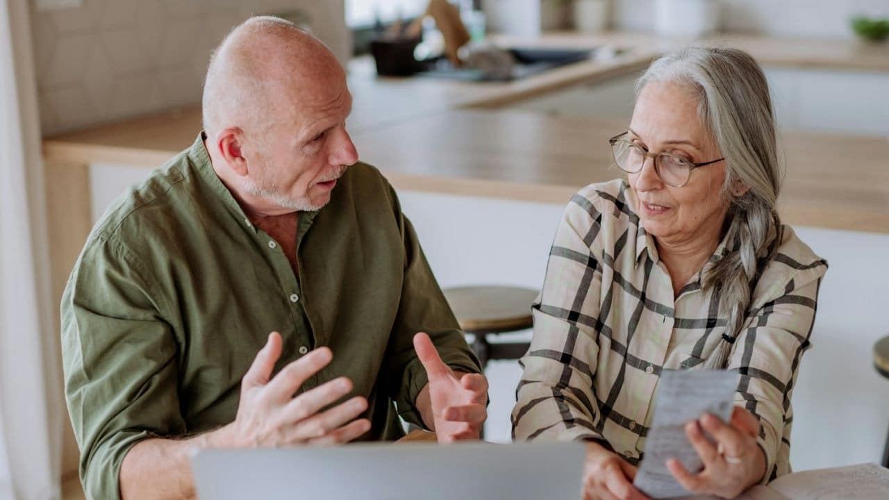 A couple appearing to be frustrated, with the man talking to the woman while she holds a paper.