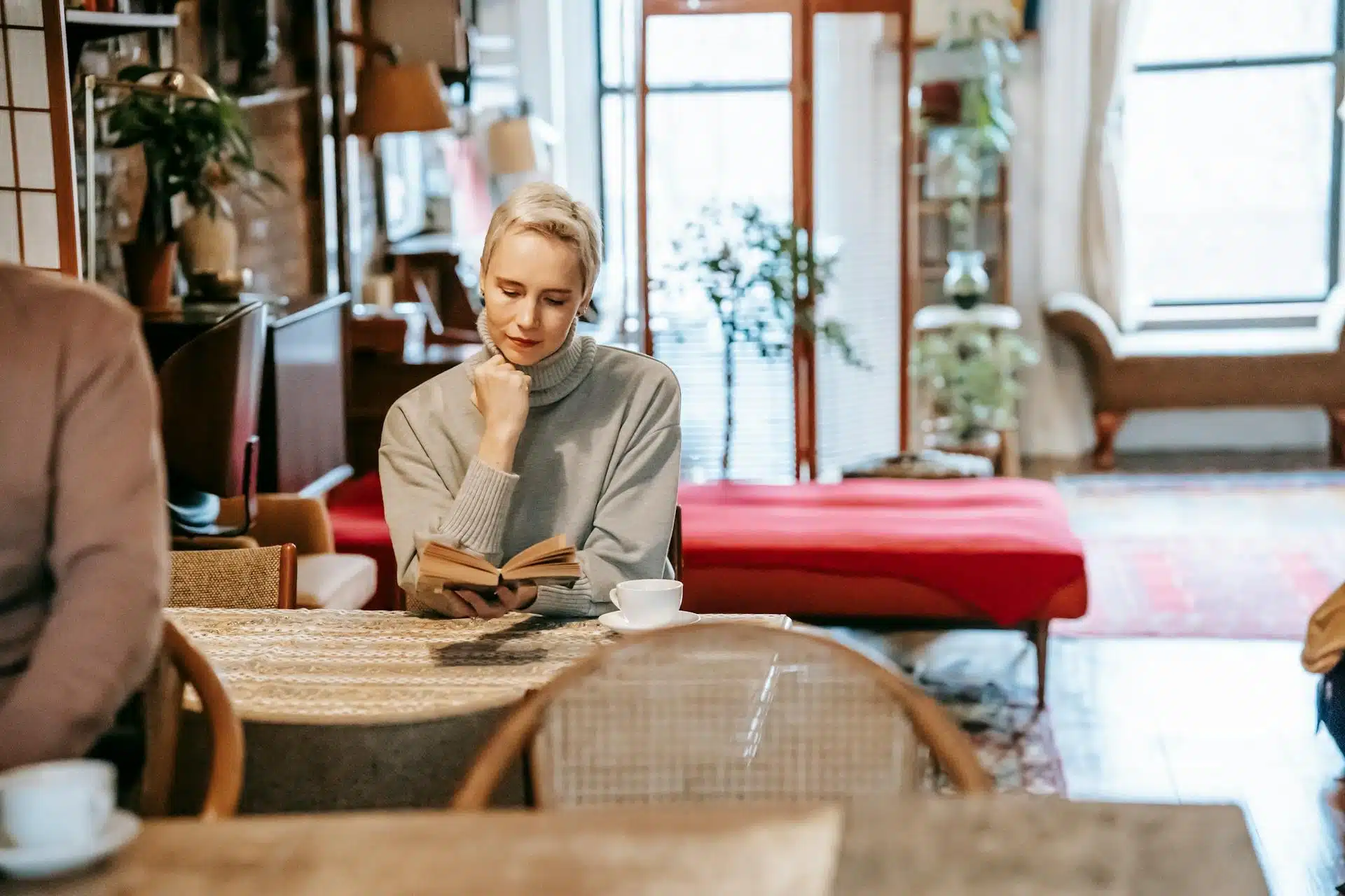 The woman is reading a book at home.