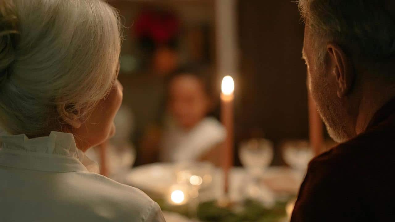 An older couple sitting together at a candlelit dinner table.