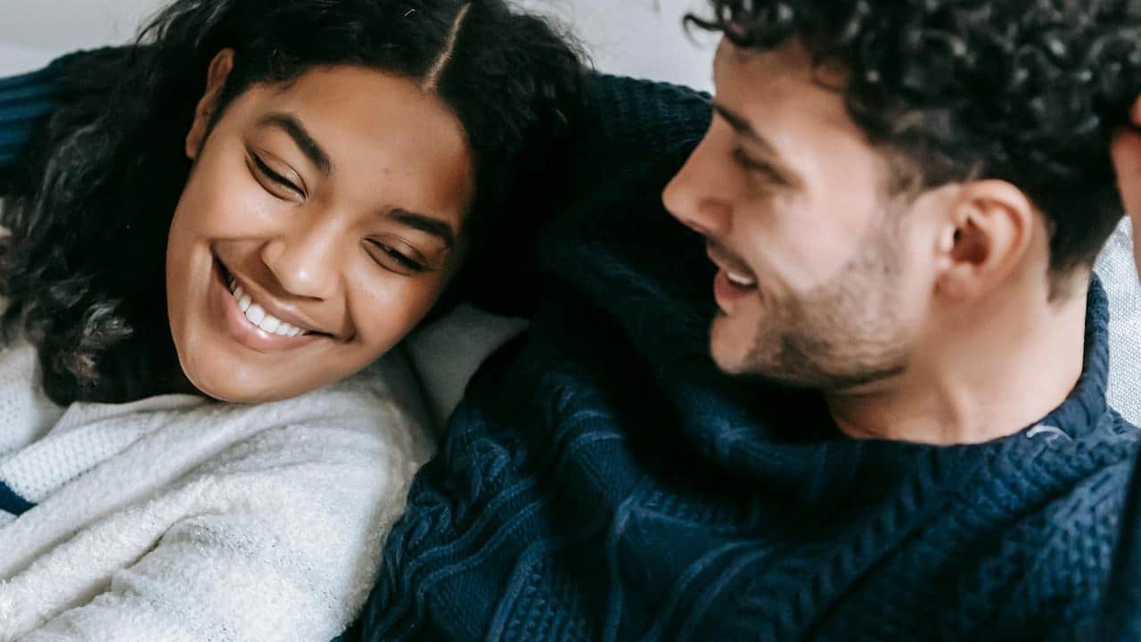 A couple smiling warmly while sitting close together.