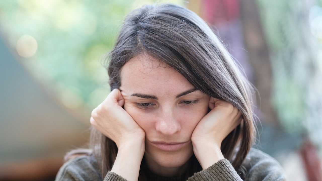 A woman looking upset and holding her face with her hands.