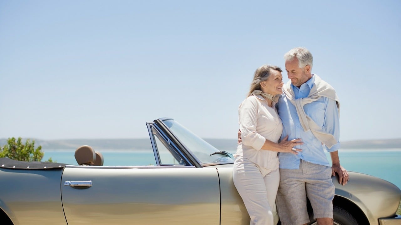 A mature couple with the woman resting her head on the man’s chest.
