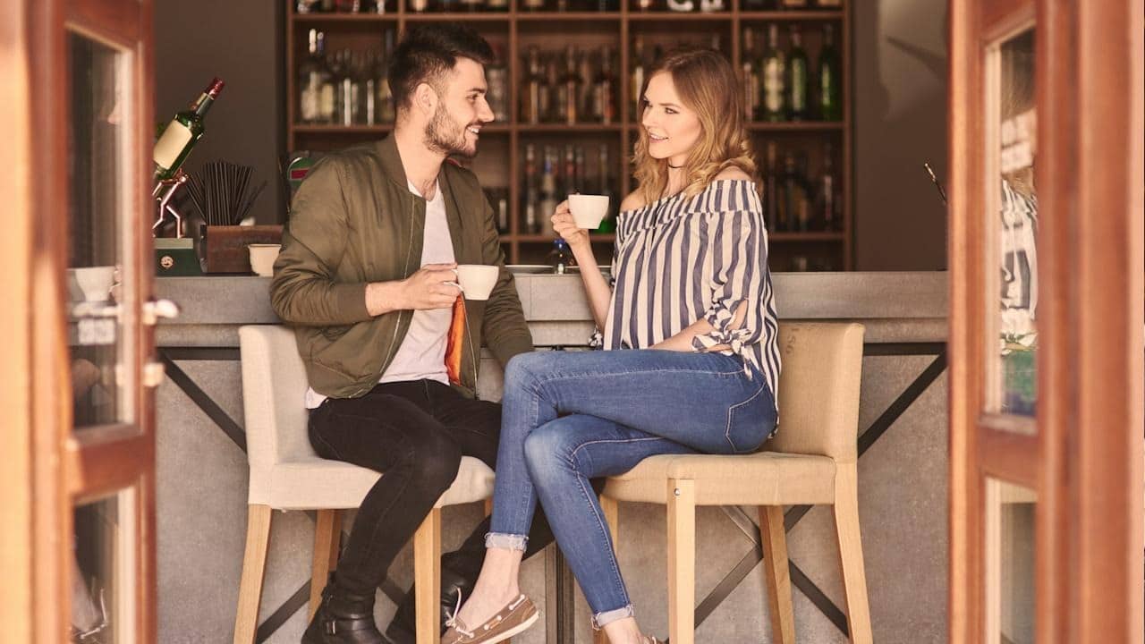 A man and woman talking and having coffee at a cafe.