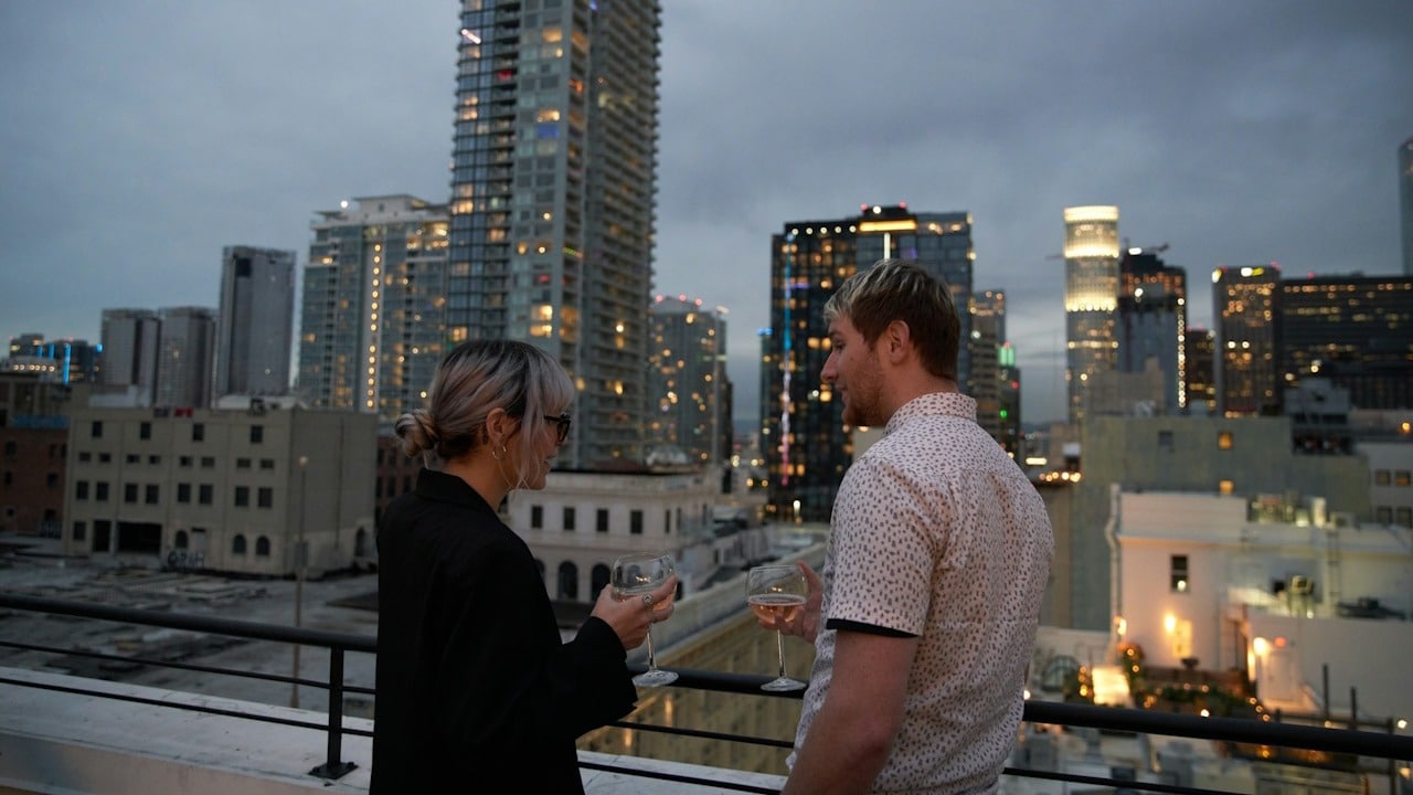 A man and a woman standing on a balcony overlooking a city