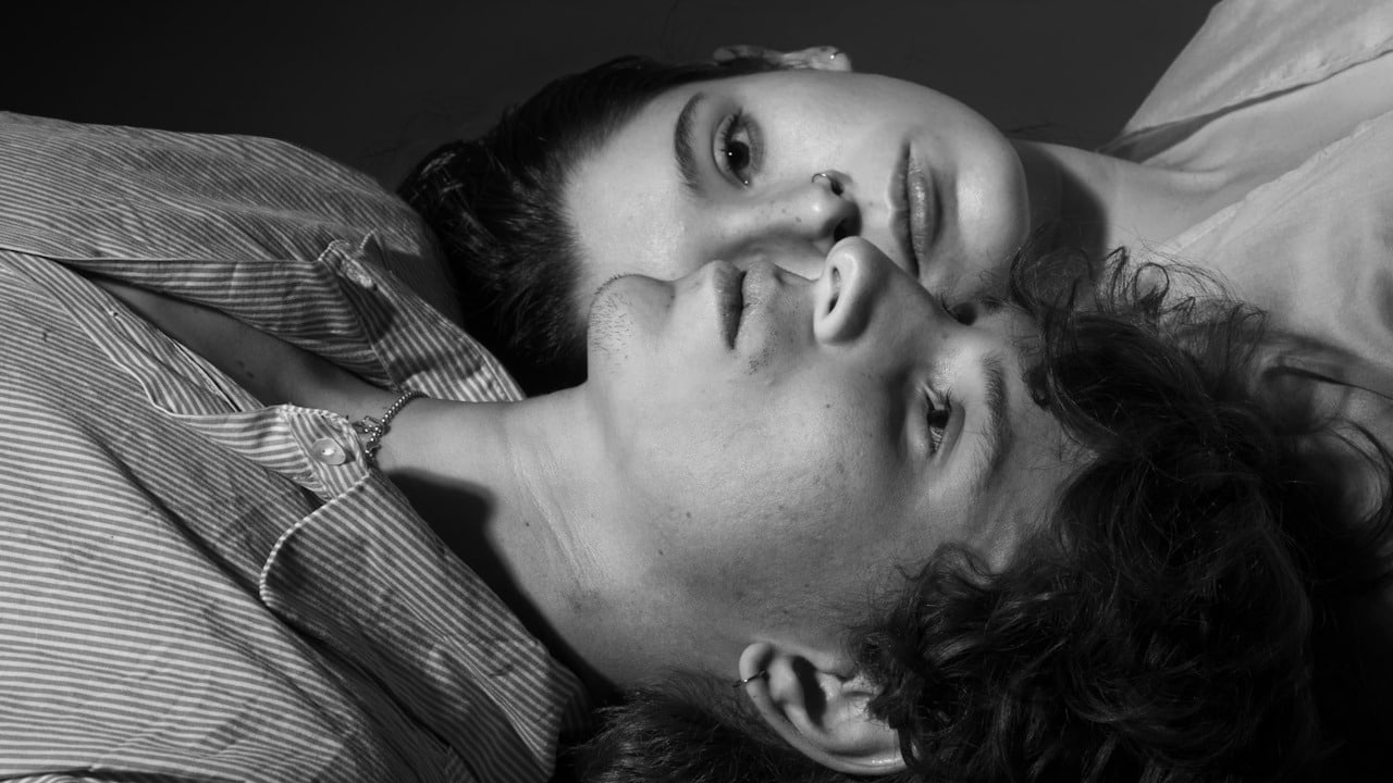 A couple lying next to each other with their heads near each other on opposite sides.