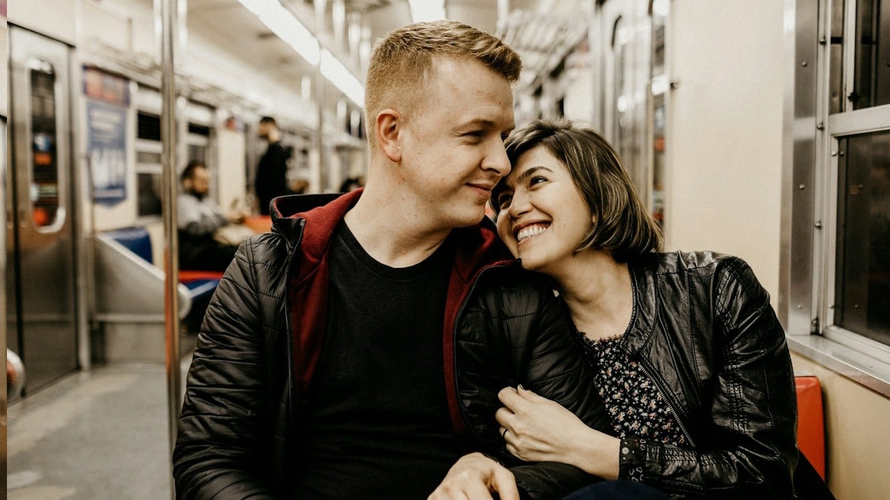 A man holding a woman's chin while they are sitting together.