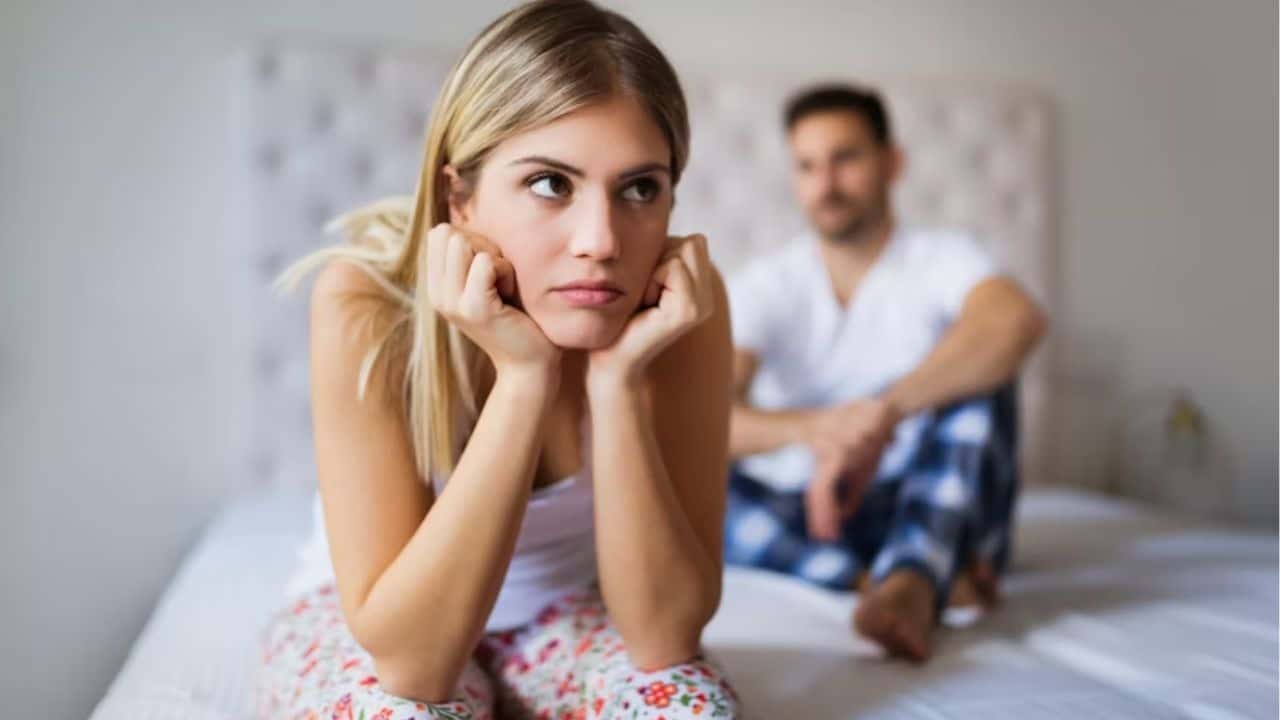 Woman sitting quietly on the couch while her partner looks away