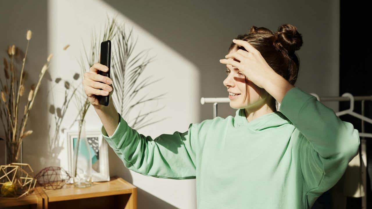 A person taking a selfie while adjusting their hair.