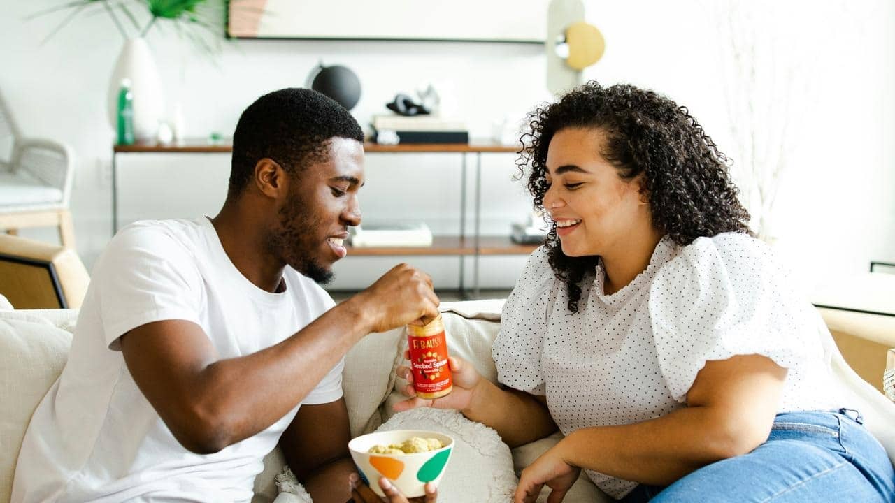 A couple on a couch sharing a snack.