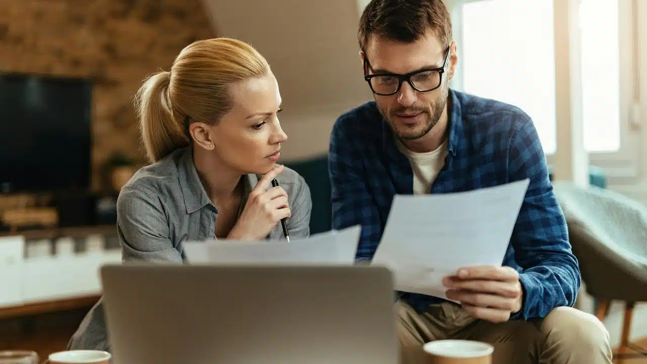 A couple reviewing documents at a laptop.