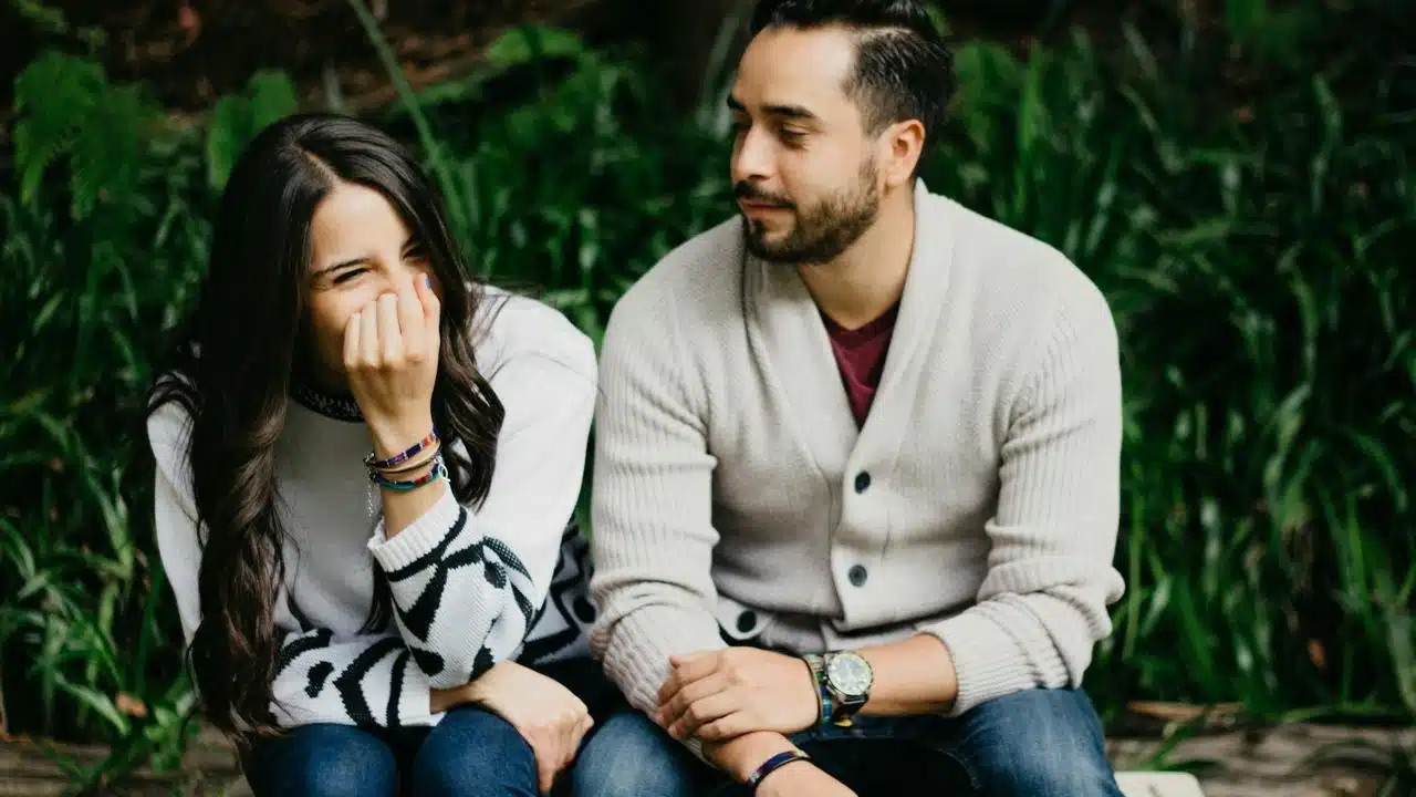 A woman laughing next to a man on a bench.