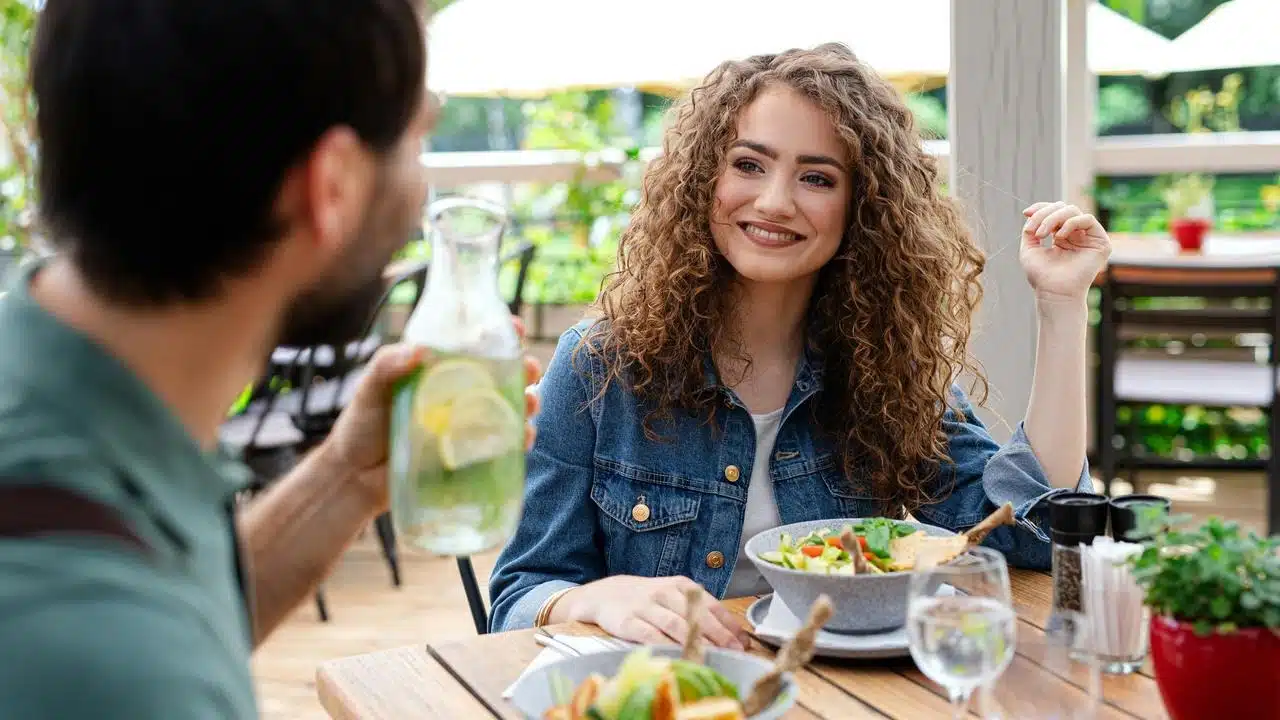 A couple eating salad at an outdoor café table.