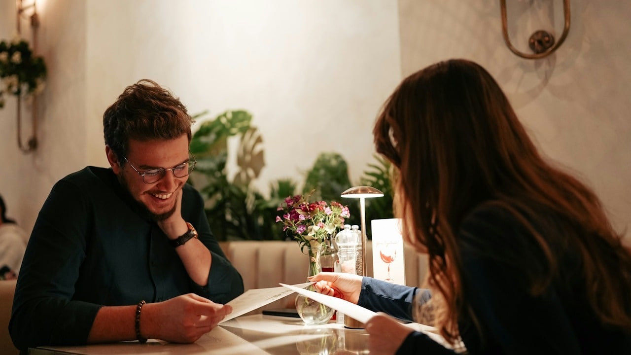 A young couple at a date looking at menu cards.
