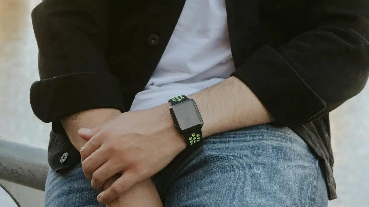 A person wearing a smartwatch with a black and green band.