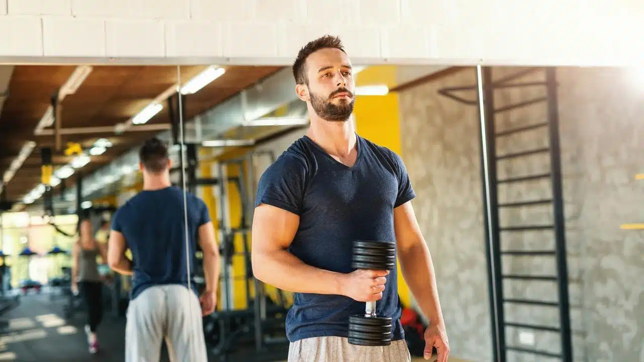 A man lifting a dumbbell in a gym.