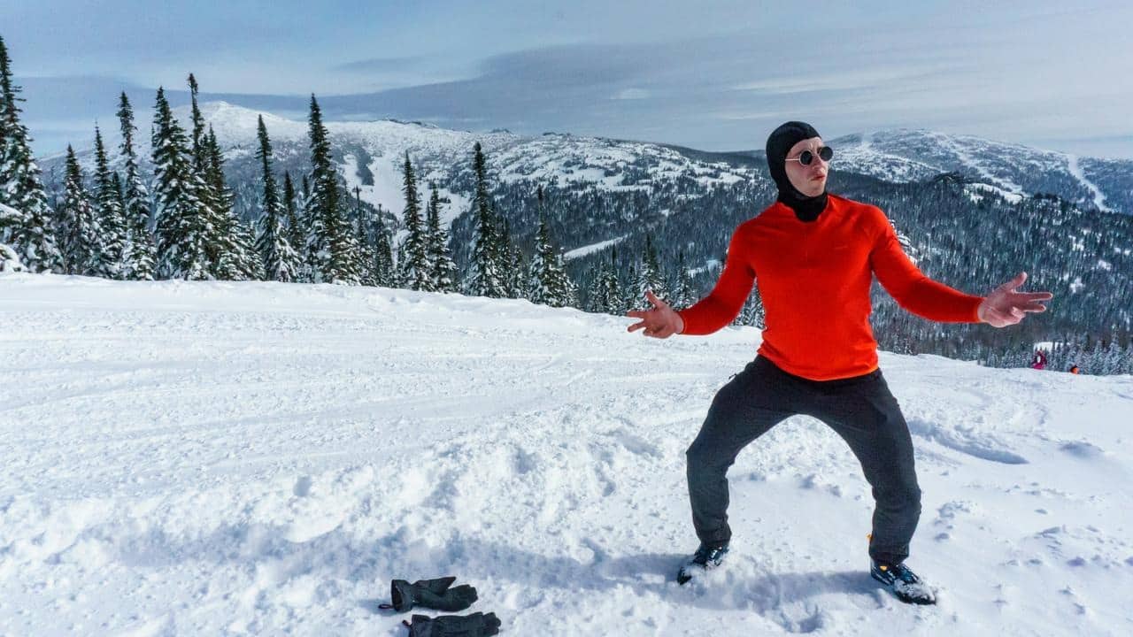 A person in red winter gear standing on a snowy mountain slope.