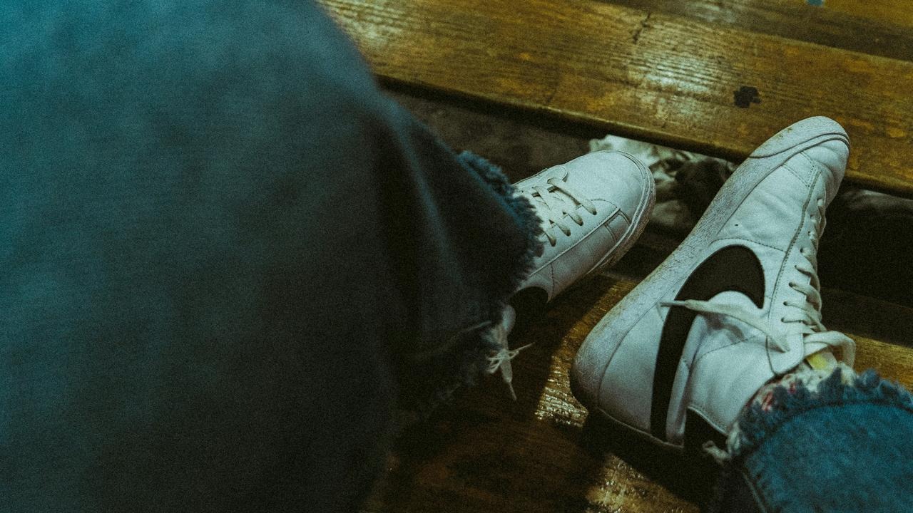 A pair of white sneakers resting on a wooden bench.