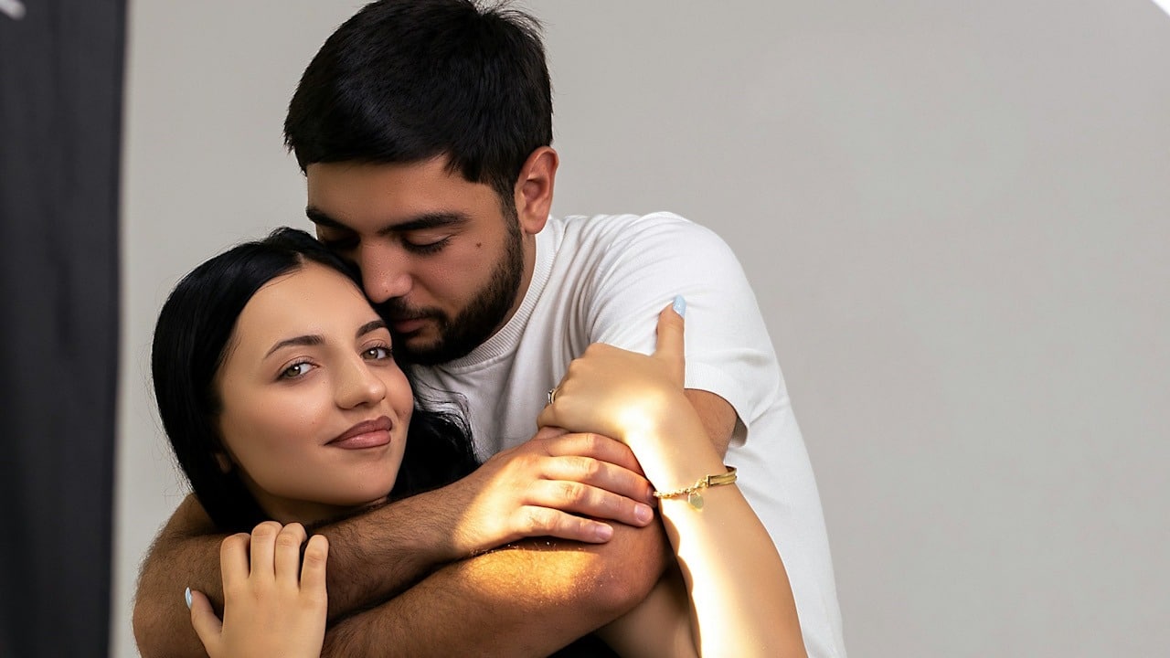 A man holding a woman tightly from behind.
