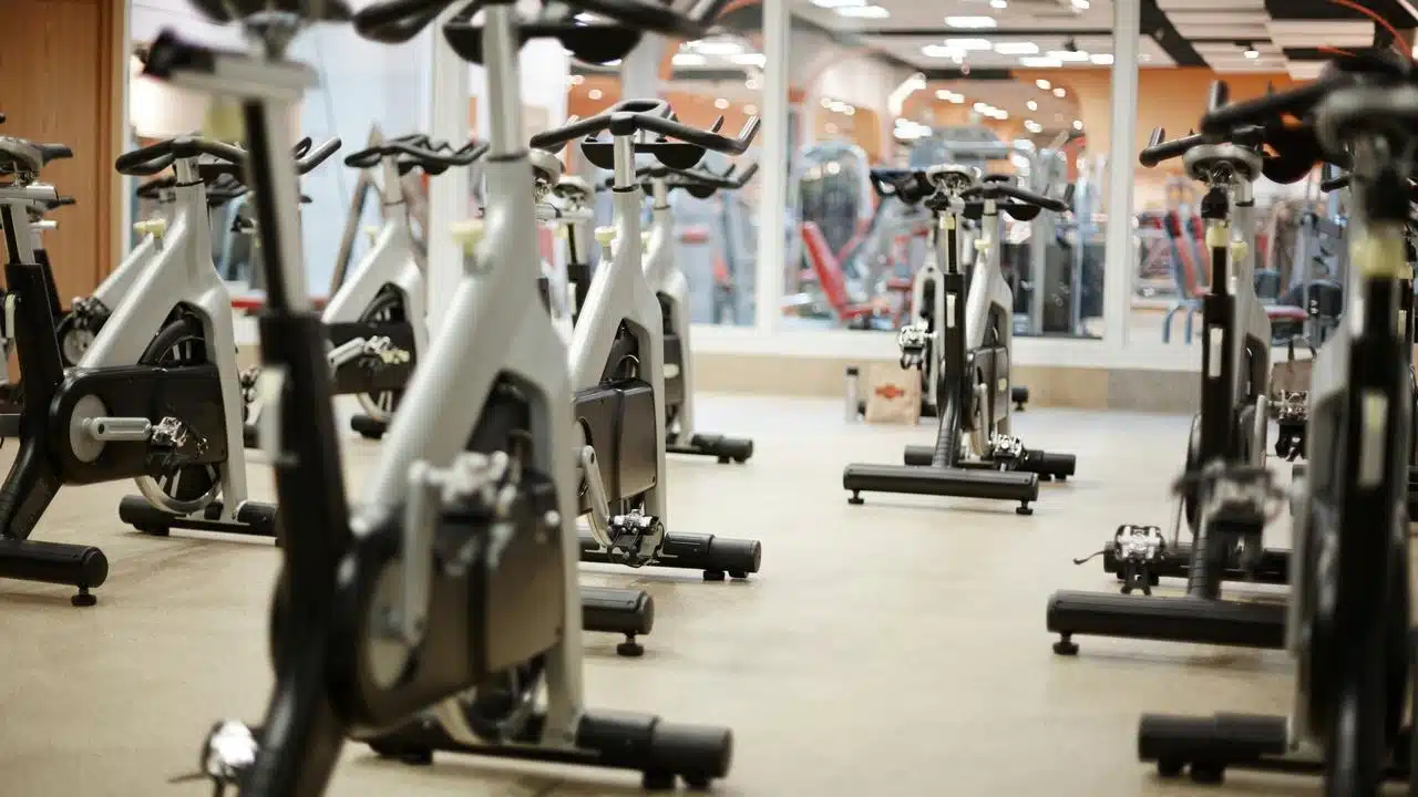 A row of stationary exercise bikes in a gym studio.