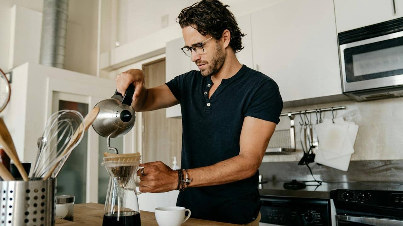 A man pouring water into a pour‑over coffee dripper.