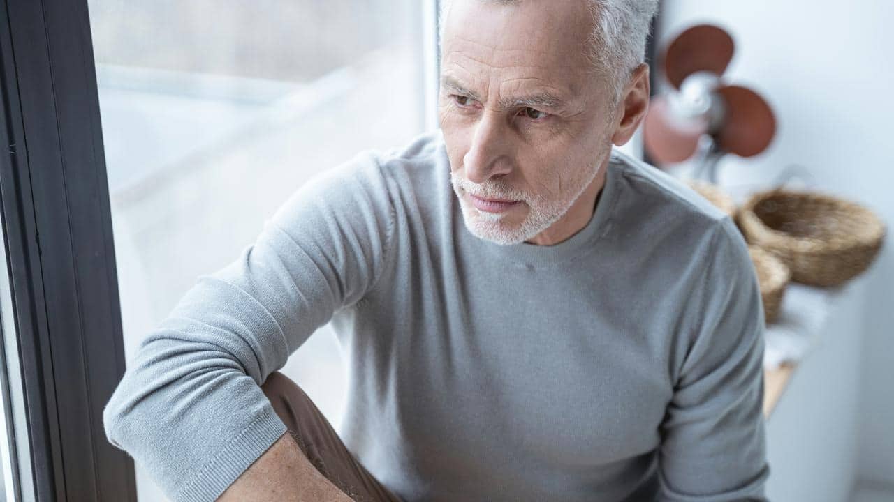 An older man gazing pensively out a window.