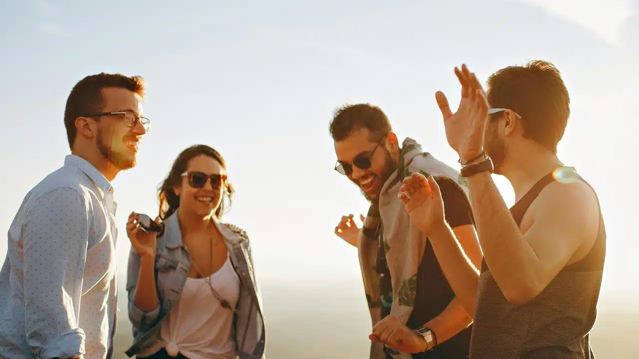 A group of friends laughing and dancing outdoors at sunset.