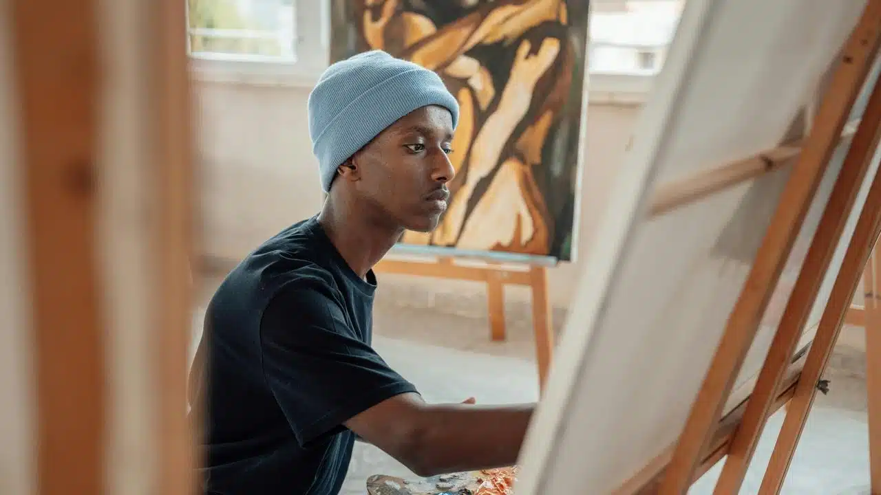 A young artist painting on a canvas at an easel.