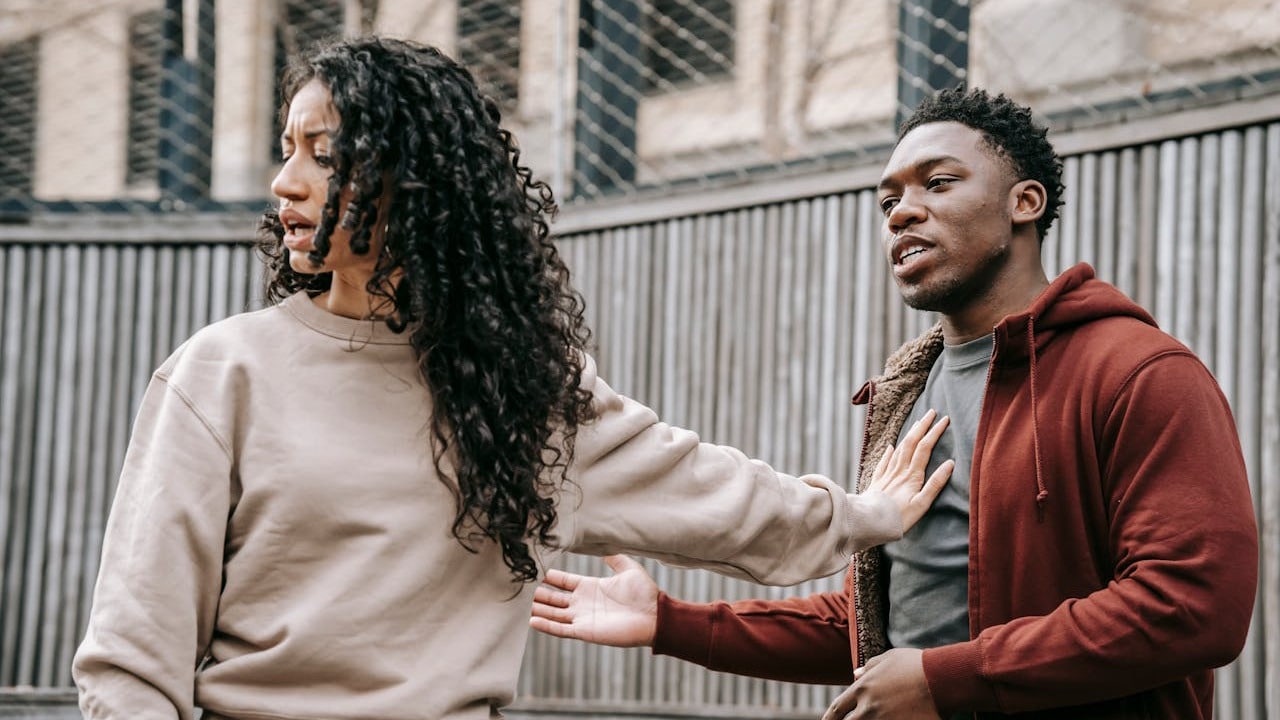 A woman pushing a man away with her arm while turning her body away from him.