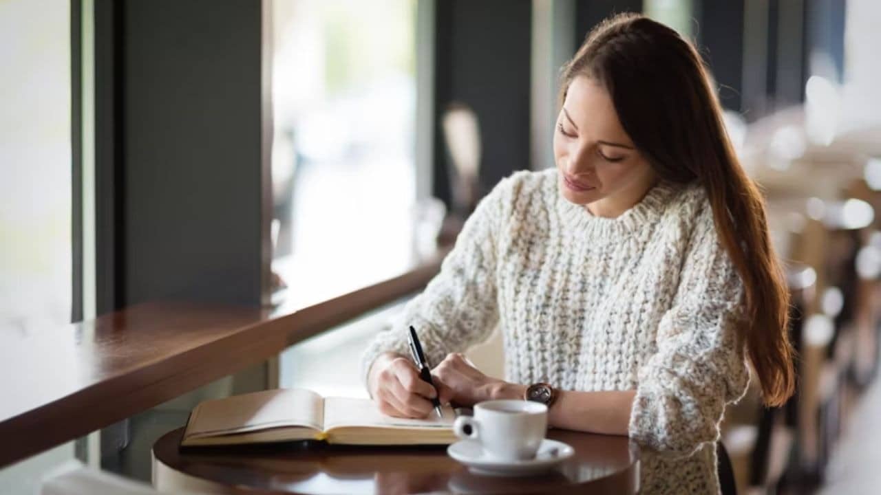 Woman journaling or reflecting alone at a coffee shop