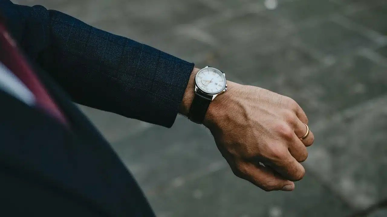 A man in a suit checking the time on his wristwatch.