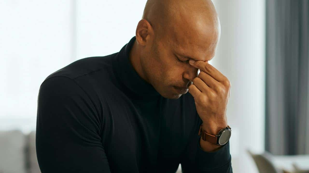 A man holding his face, looking stressed.