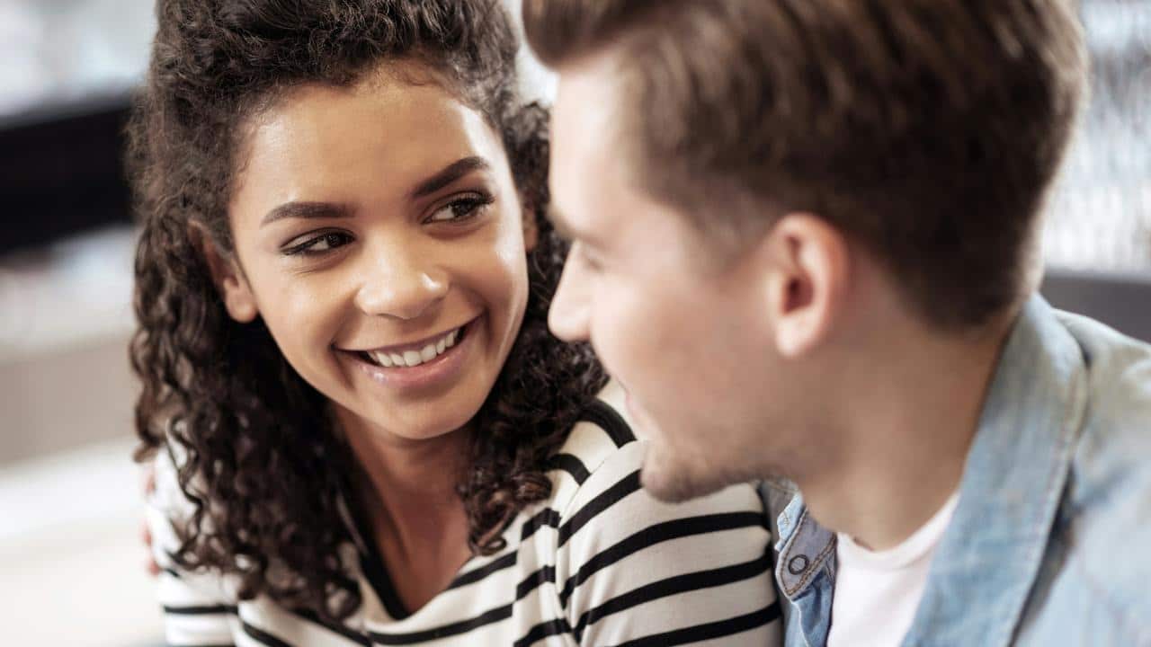 A woman smiling warmly at a man during a conversation.