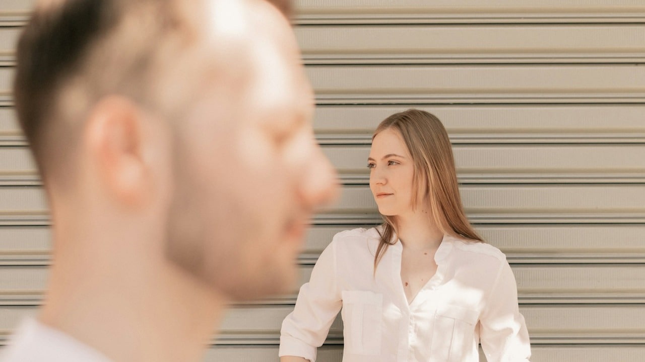 A woman looking to the side while a man stands in the forefront.