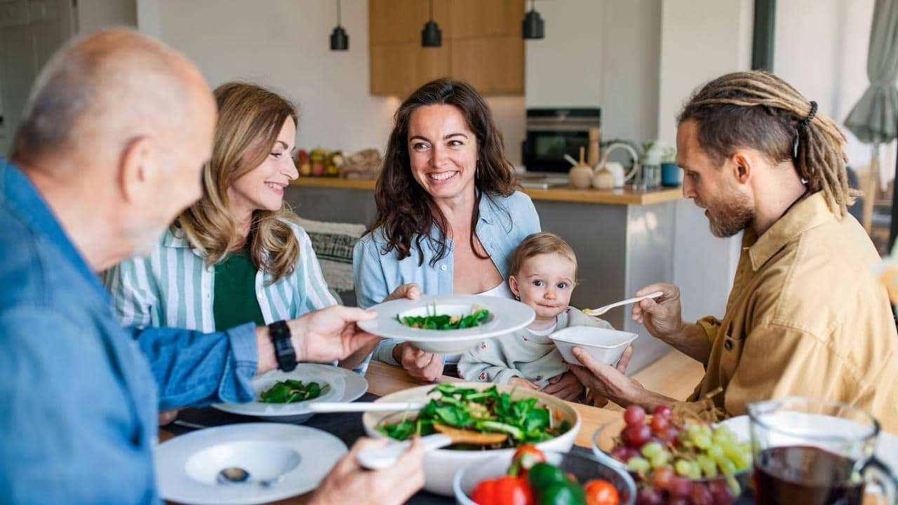 A family sitting at a table enjoying a meal together with a baby.