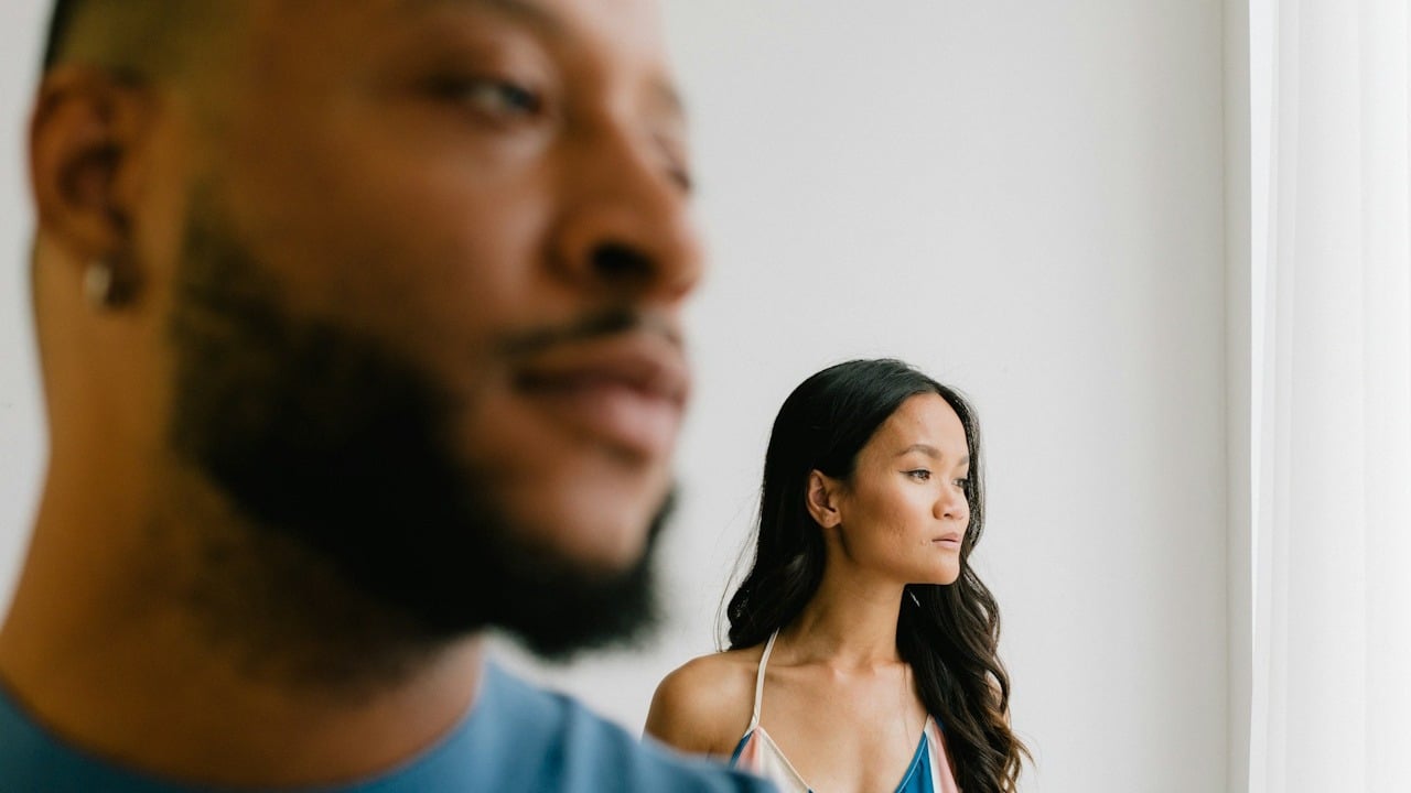 A couple standing separately are looking at one side of the room.