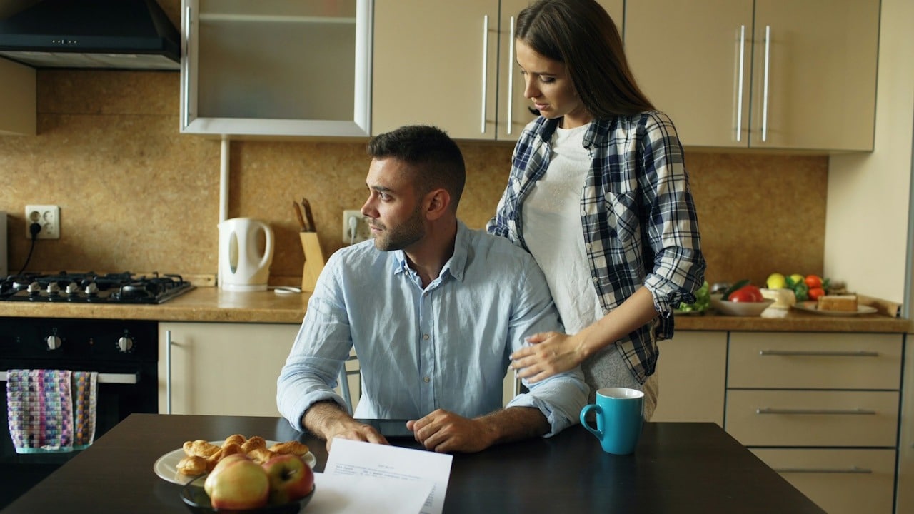 A man is worried to pay monthly bills and his wife is consoling him.