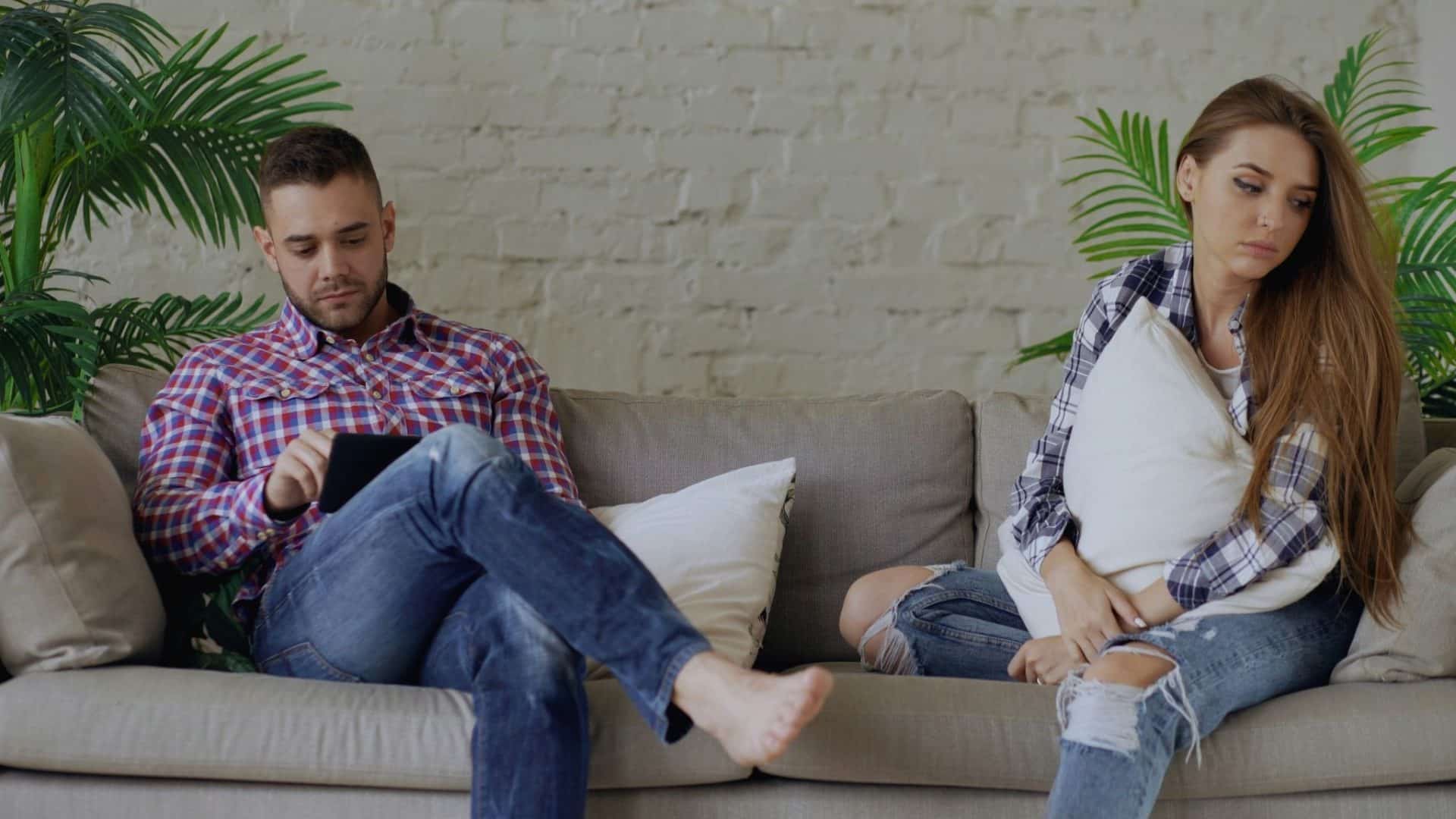 A sad woman sitting beside the busy man