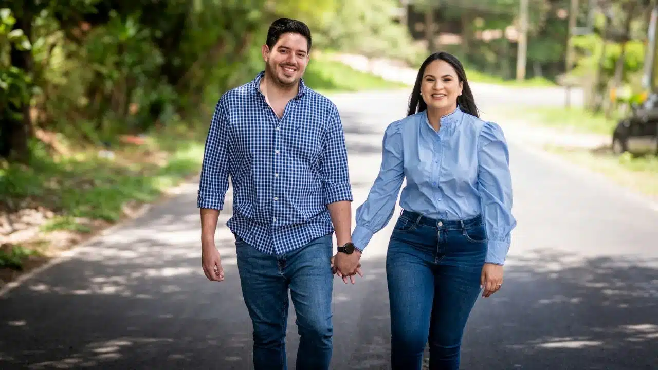 A smiling, happy couple is walking hand in hand on a sunny day.
