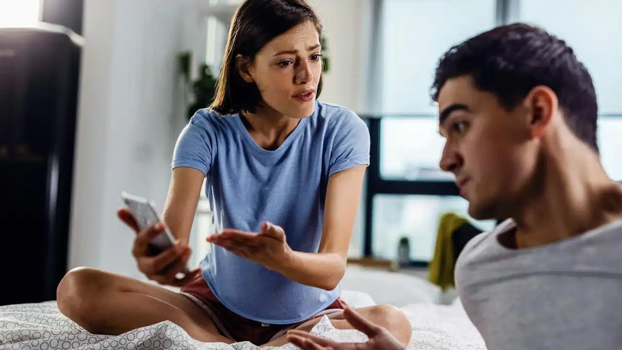 A woman showing a man something on her phone and accosting him.