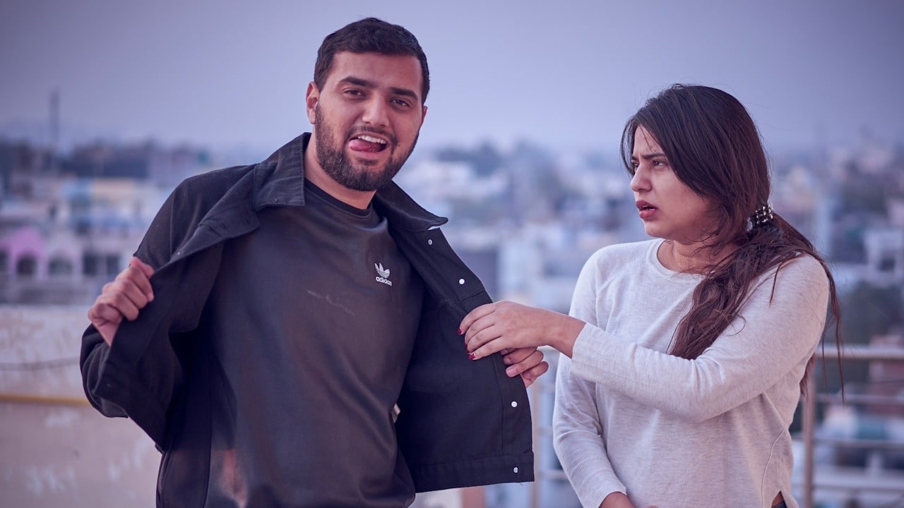A woman holding jacket of man and the man is trying to annoy her.