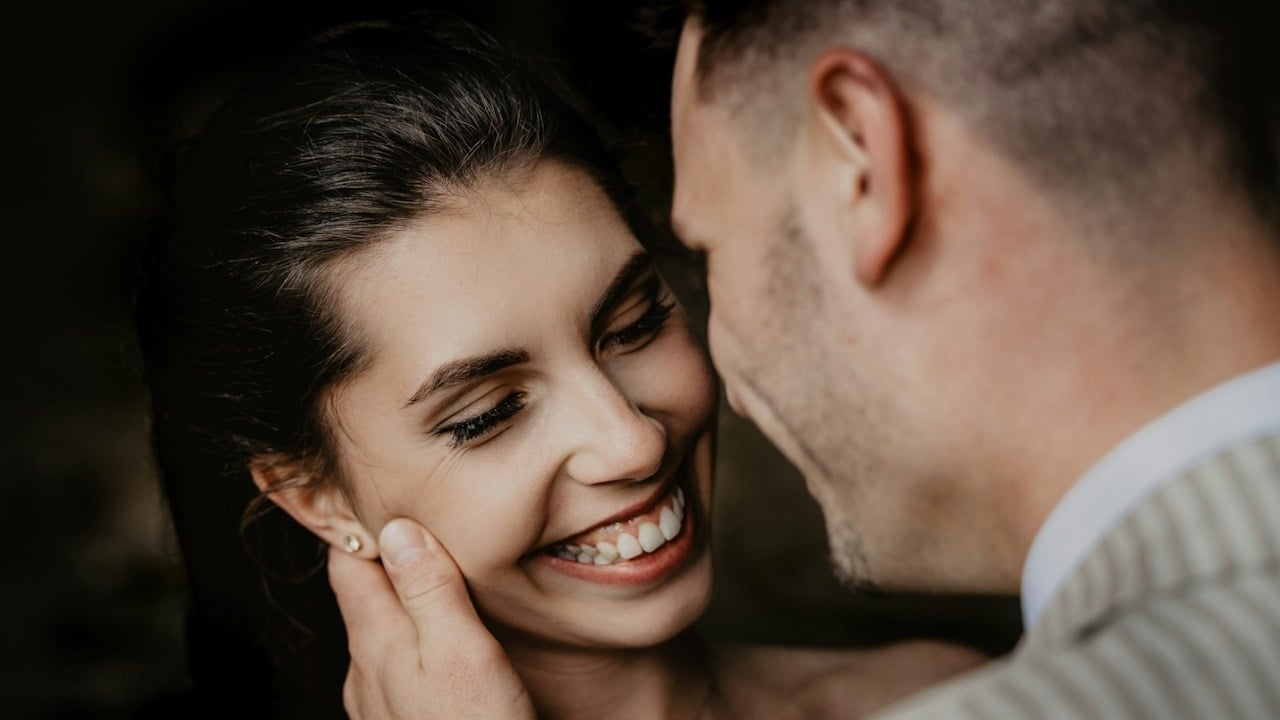 A man and woman smiling while standing close to each other.