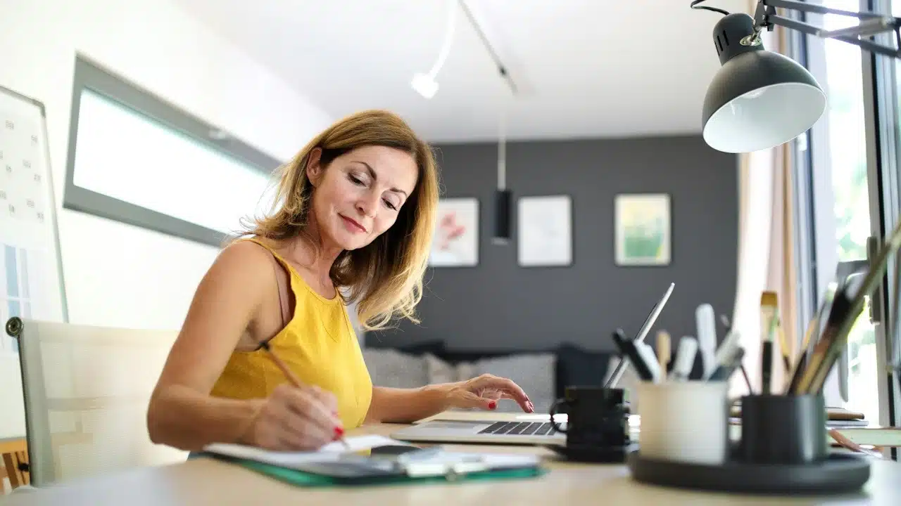 A mature woman working indoors in a home office in a container house in a backyard.
