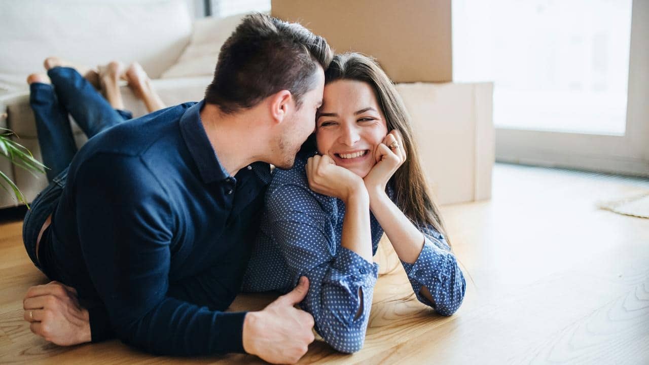 A couple laying on the floor and sharing a happy moment together.