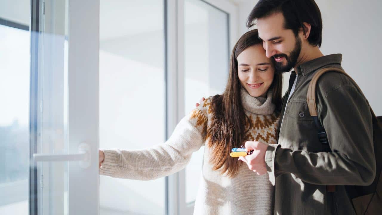 A couple standing by a window and staring at house keys.