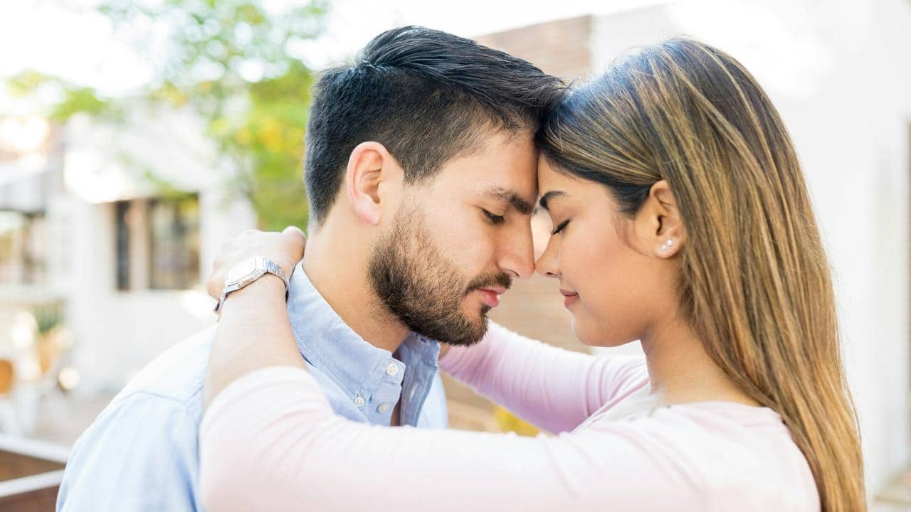 A man and a woman closely bumping their foreheads together with their eyes closed.