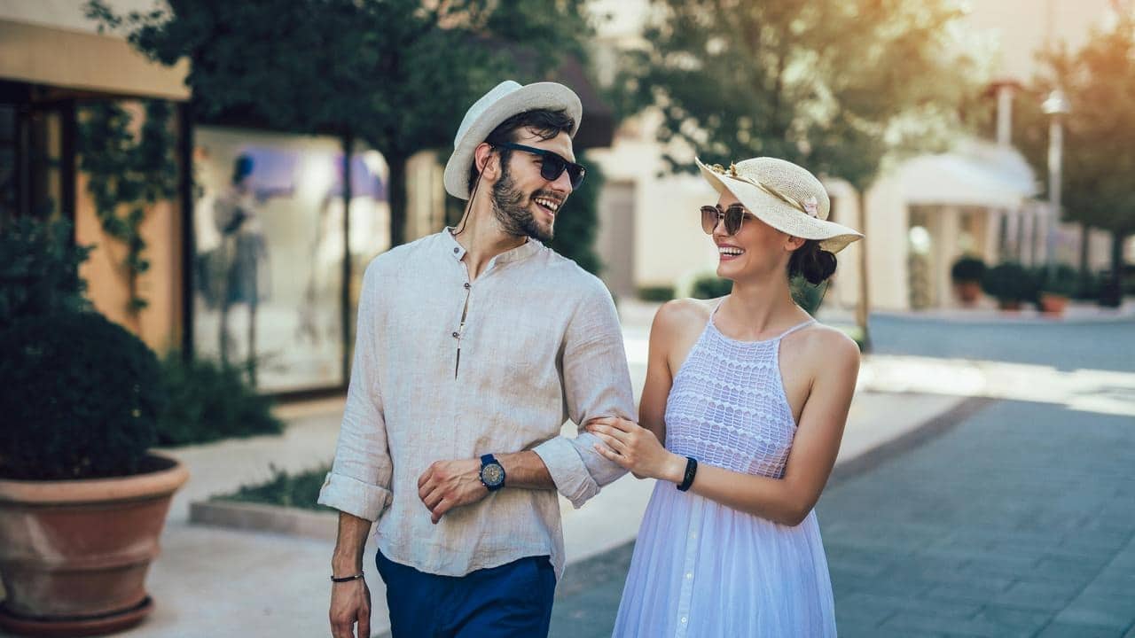 A smiling couple walking arm in arm on a sunny day.