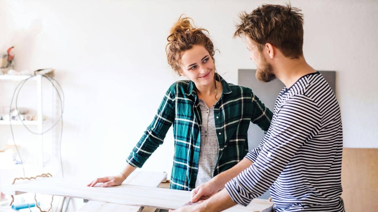 A couple discussing a woodworking project indoors.
