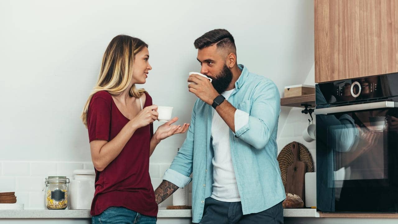A couple sharing coffee in a kitchen.
