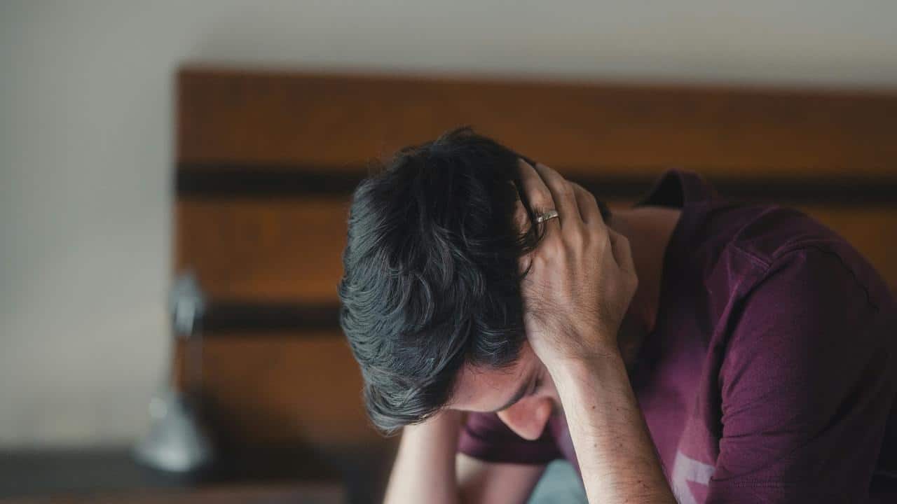 A man sitting with his head in his hands looking stressed.
