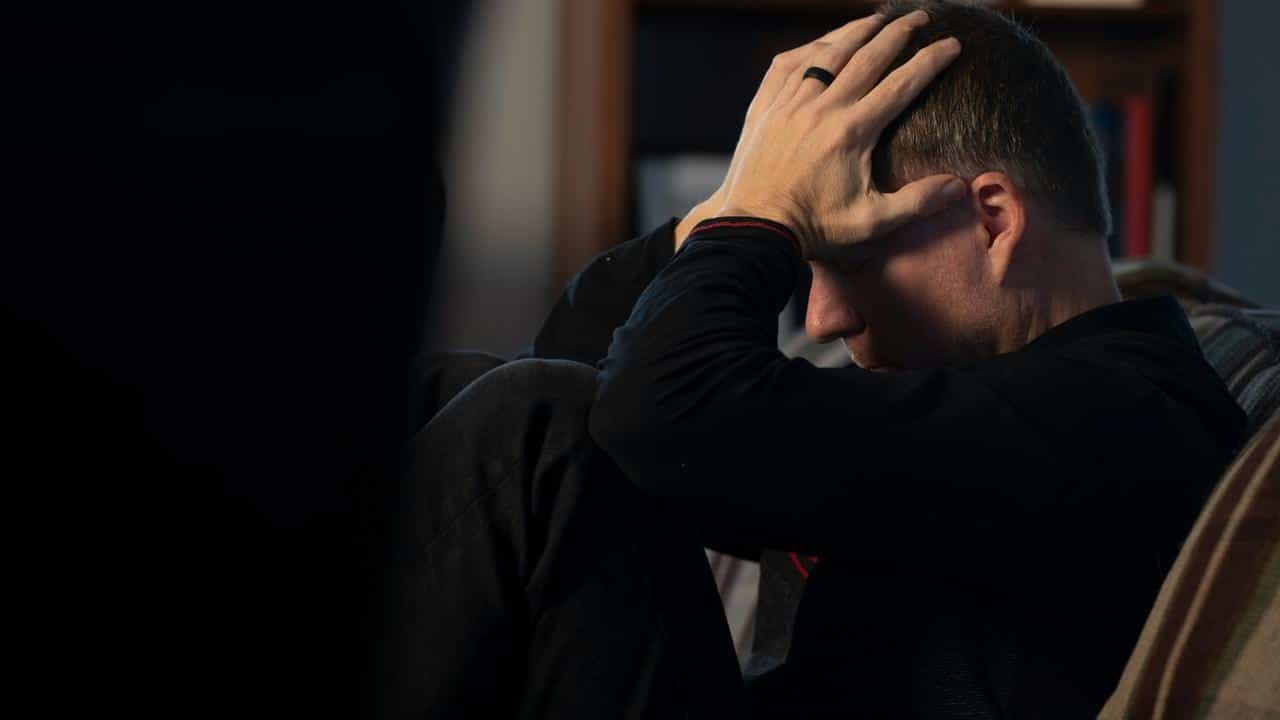 A man sitting with his head in his hands looking distressed